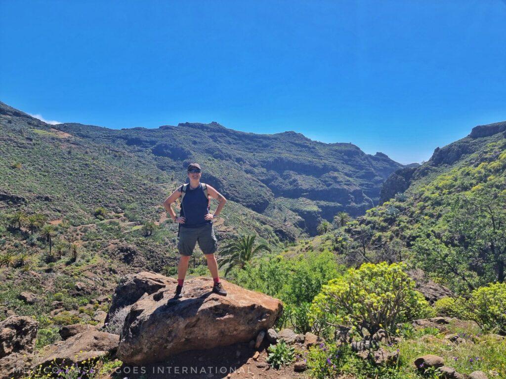 Cassie standing on a rock with mountains and wild flowers all around