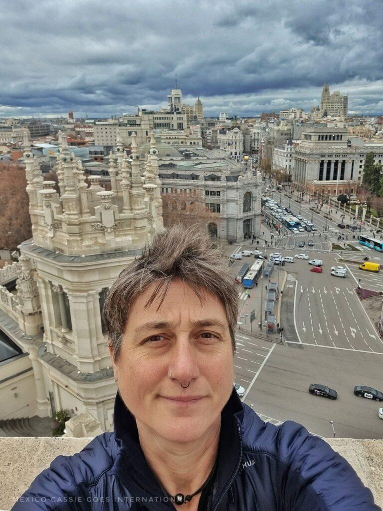 Cassie taking a selfie (wearing blue jacket) with view of Madrid street behind - taken from mirador in Palacio de Cibeles

