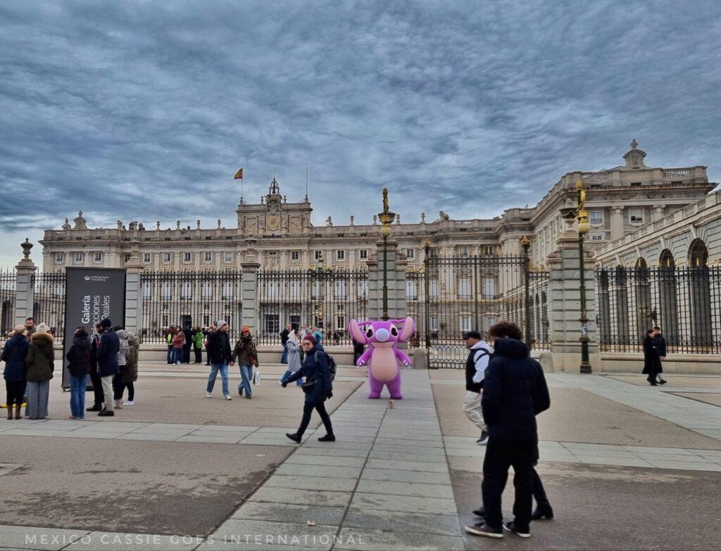royal palace of madrid with a pink mascot costumed person standing in front
