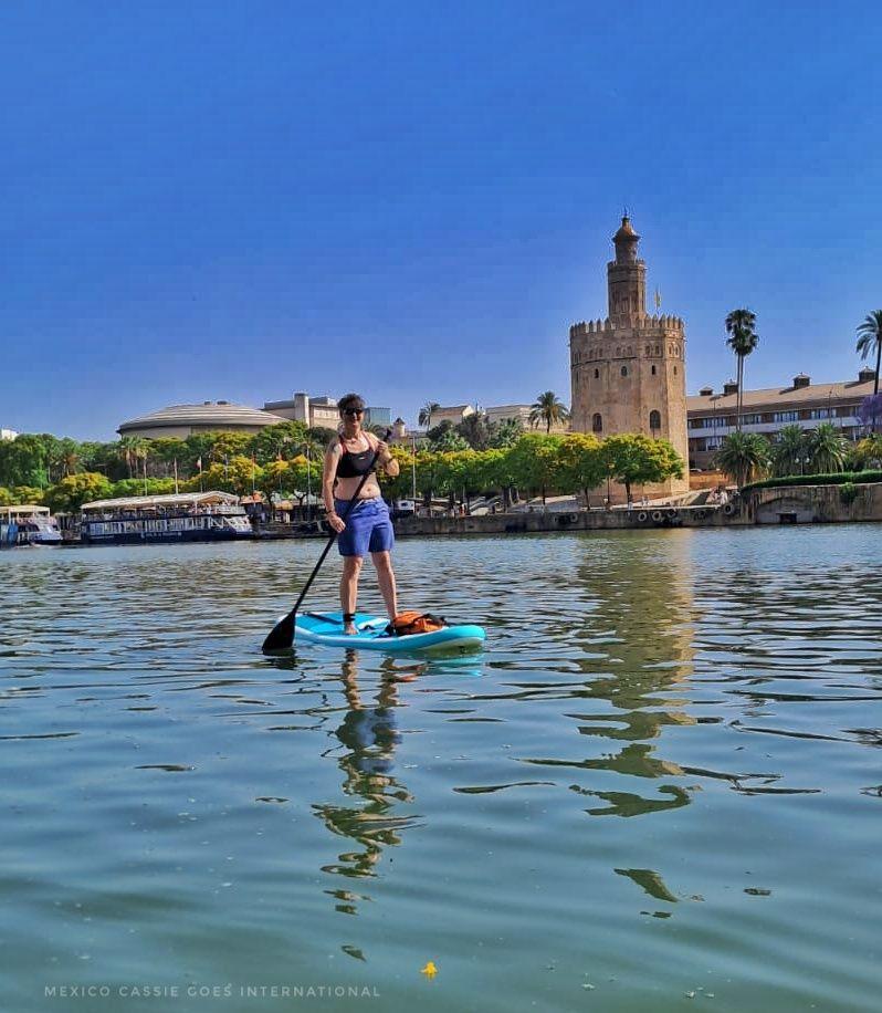 Cassie on a paddle board on the river in front of the Torre del Oro