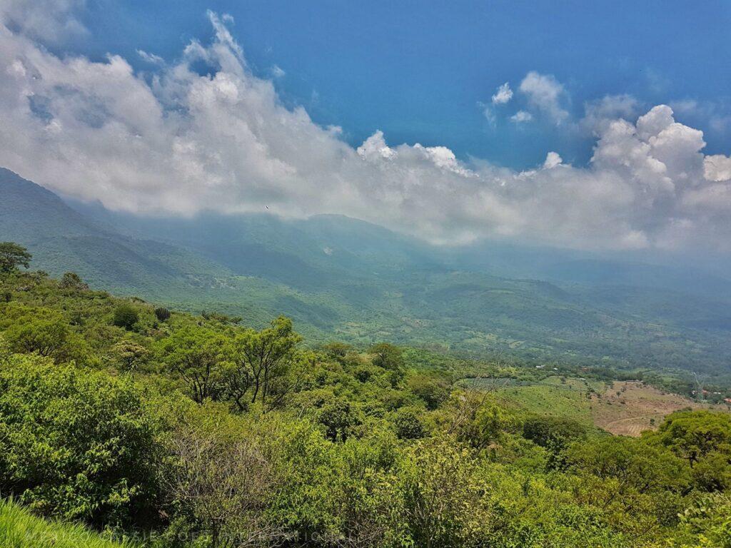 view of countryside, from mountain top - over trees to hills in distance, clouds