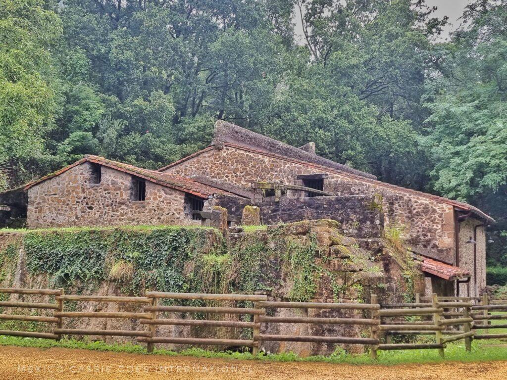 old iron mill surrounded by trees. fence around it