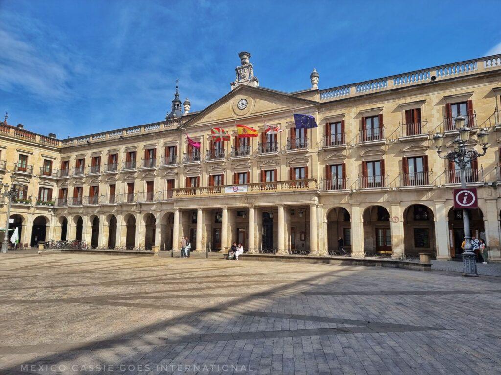 big, empty plaza with imposing building all around - flags, columns, windows