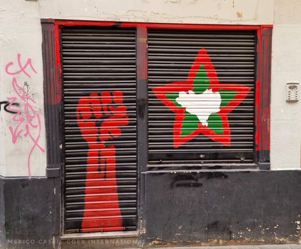 door and window covers painted with red arm of protest and red/green star with shape of Basque country inside it