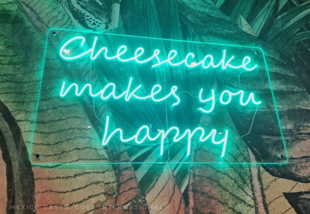 green neon sign that reads "cheesecake makes you happy"
