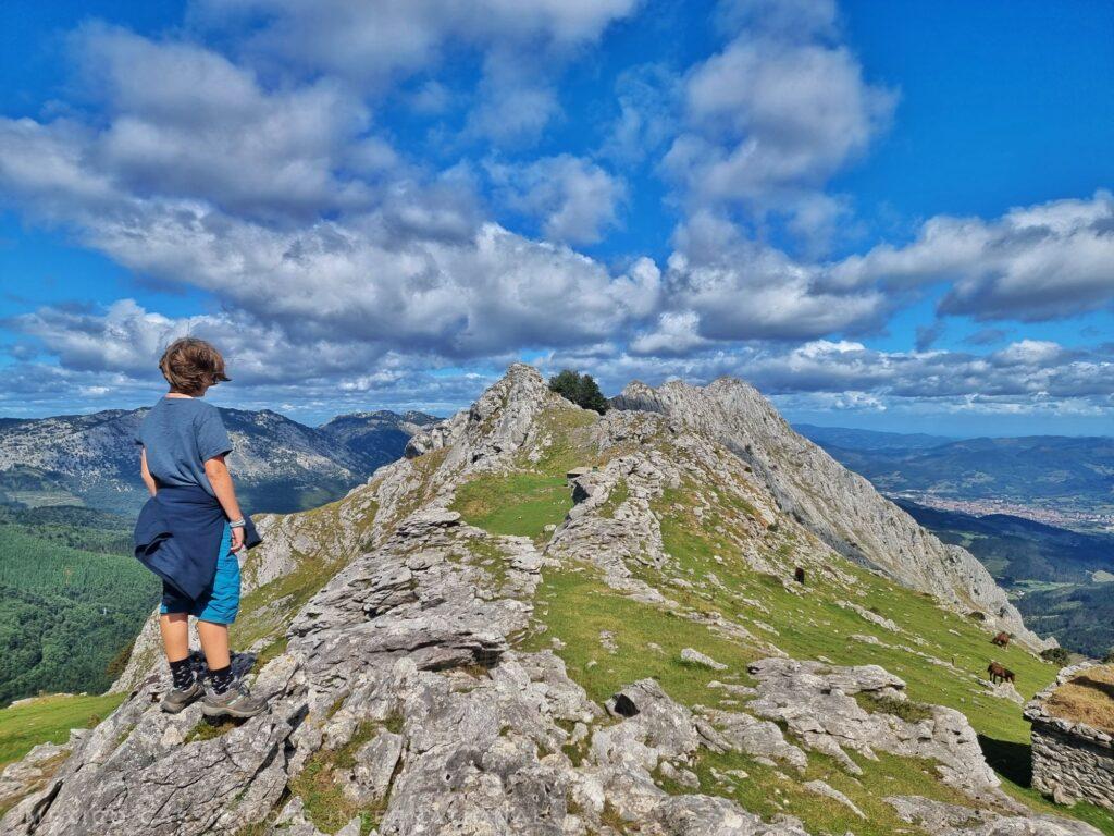 kid standing on mountain rock looking into distance