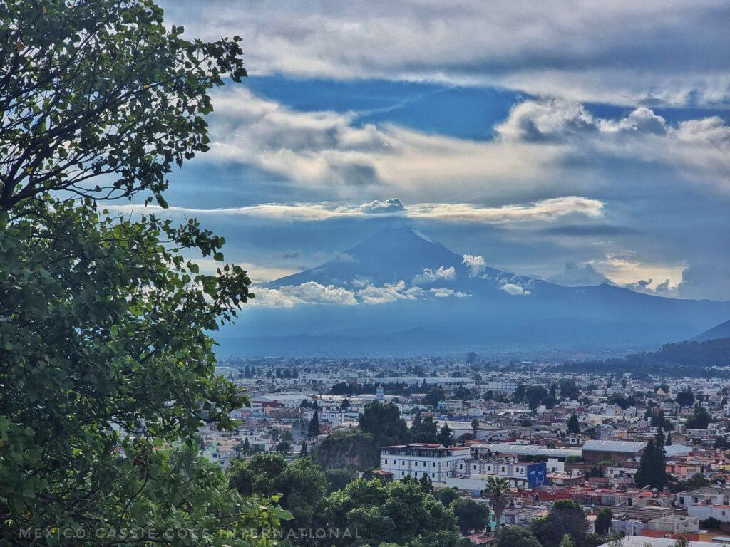 cloudy view of a volcano behind a city