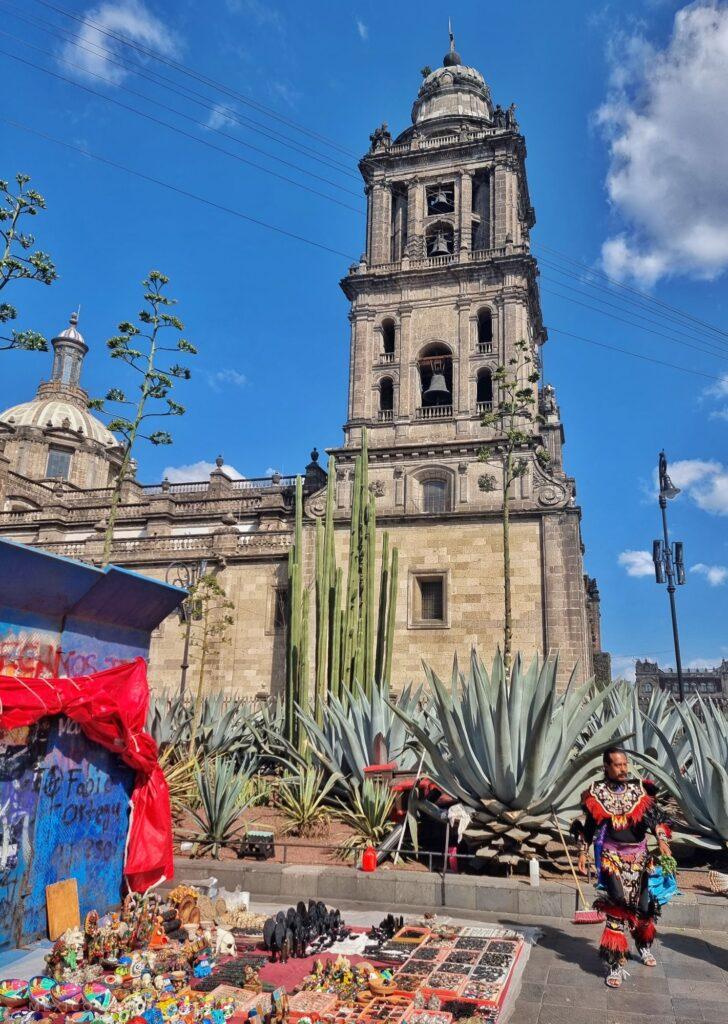 Mexico City cathedral, zocalo. Artisan stall and man in Aztec costume, cacti