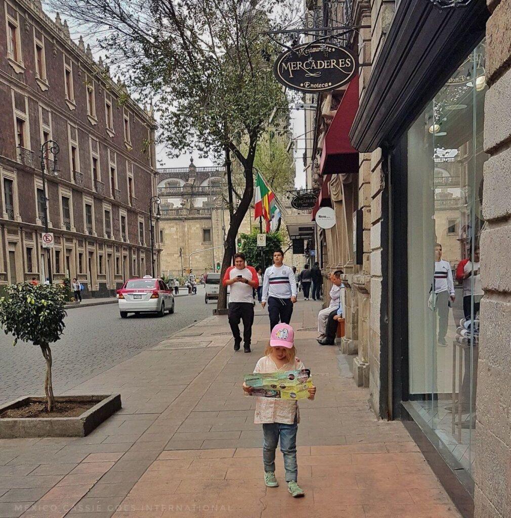 small child walking on street looking at a map