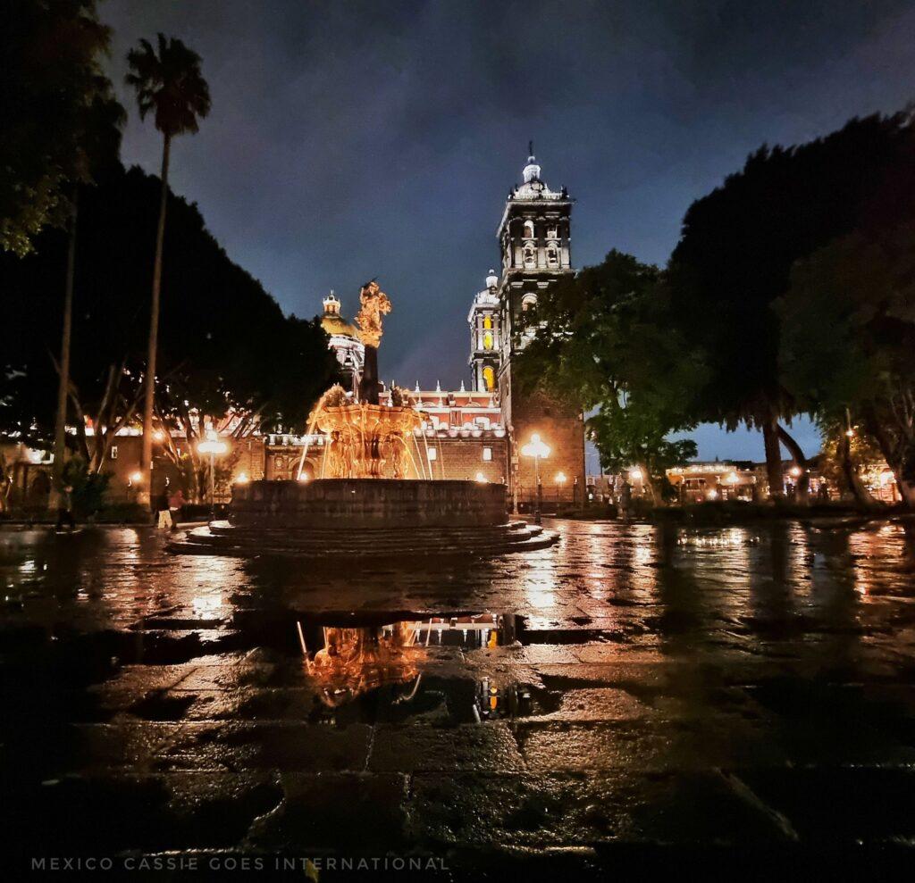 Puebla zocalo on a dark and wet night - reflection of fountain in puddle