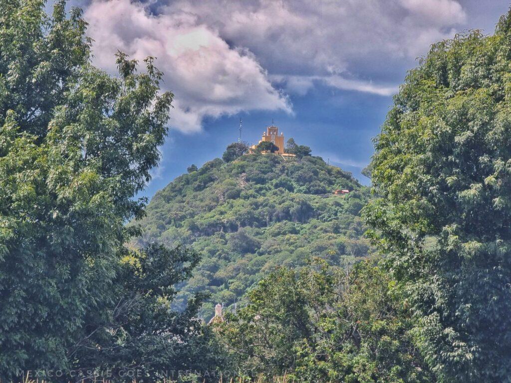 Cerro de San Miguel (green hill with church on top) seen through trees