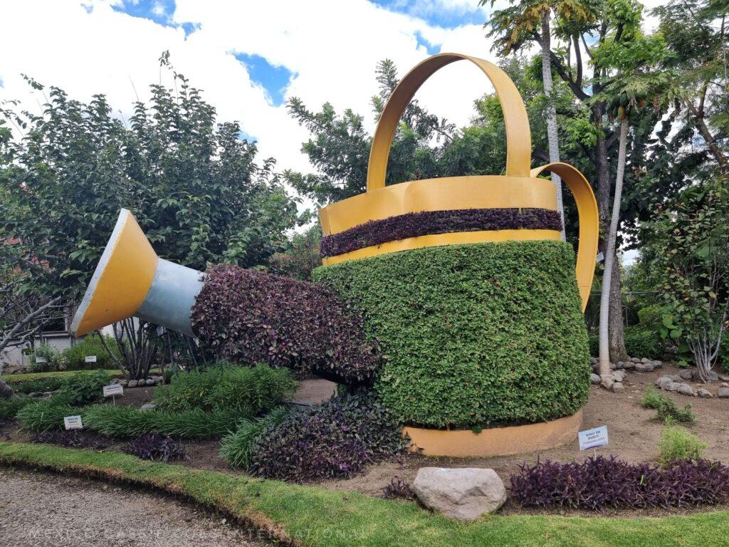 giant watering can with some of it made of plants