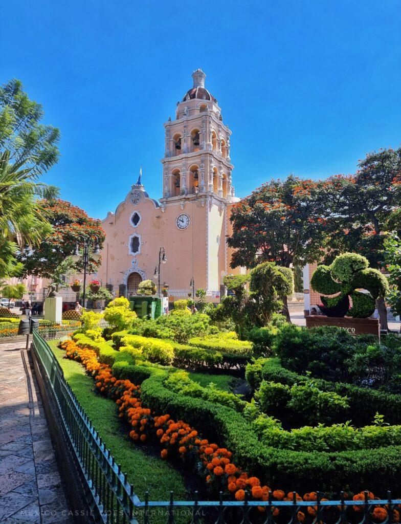pinkish church, blue sky, flower bed