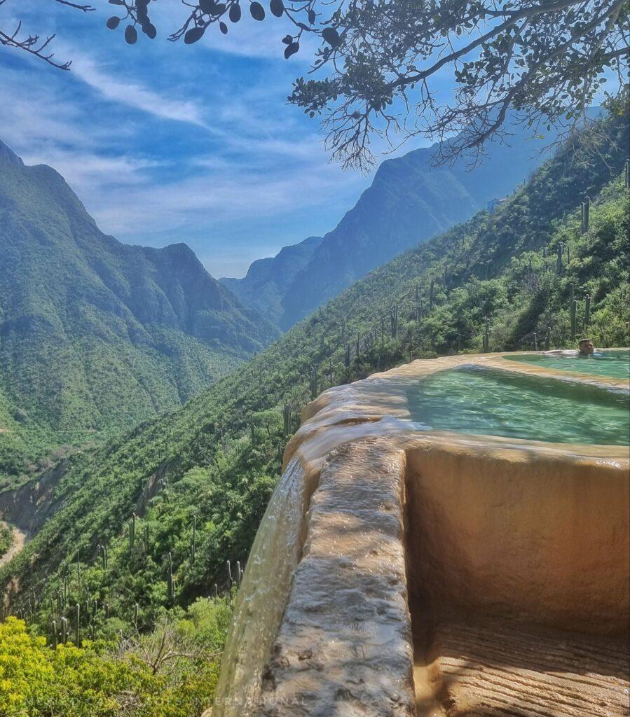 infinity pool with water cascading over side, mountain views behind