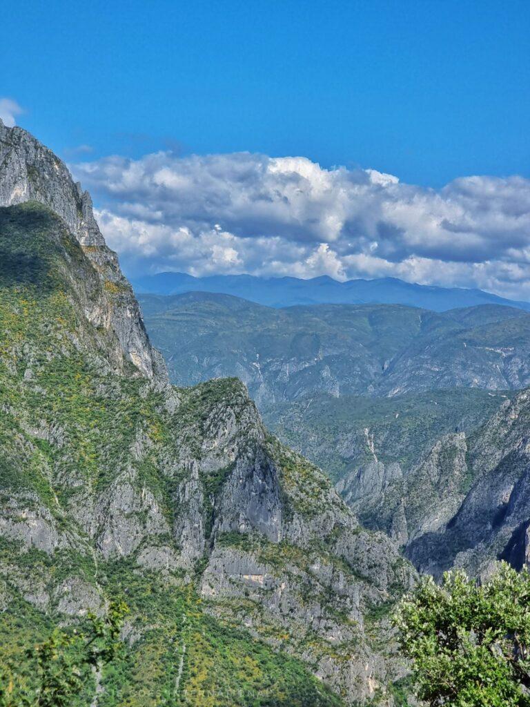 looking out of a green, mountainous valley, clouds and blue sky