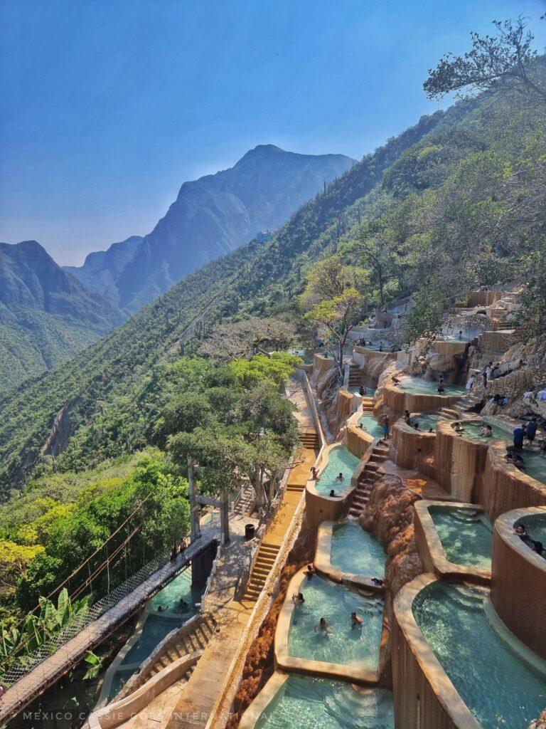 mountain scene, pools of very blue water, few people in them