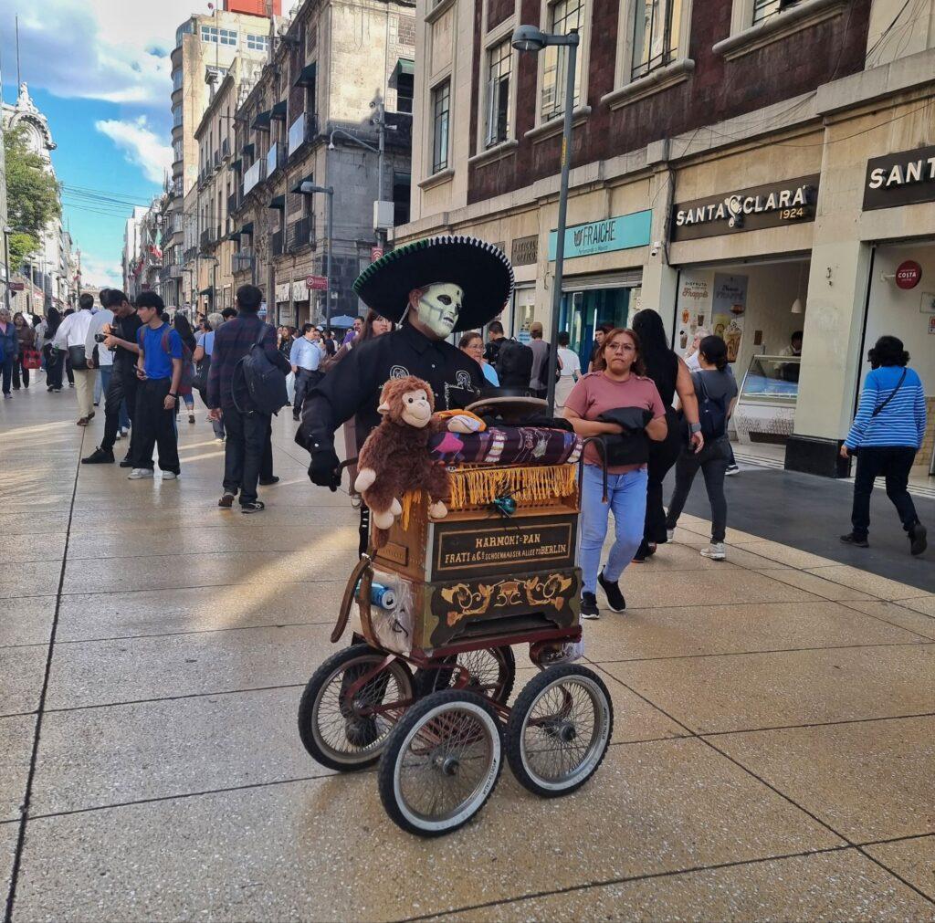 man dressed as a skeleton for día de muertos working his traditional music machine