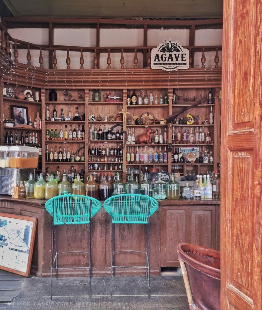 looking into a bar that has 2 green bar chairs in front of old wooden bar