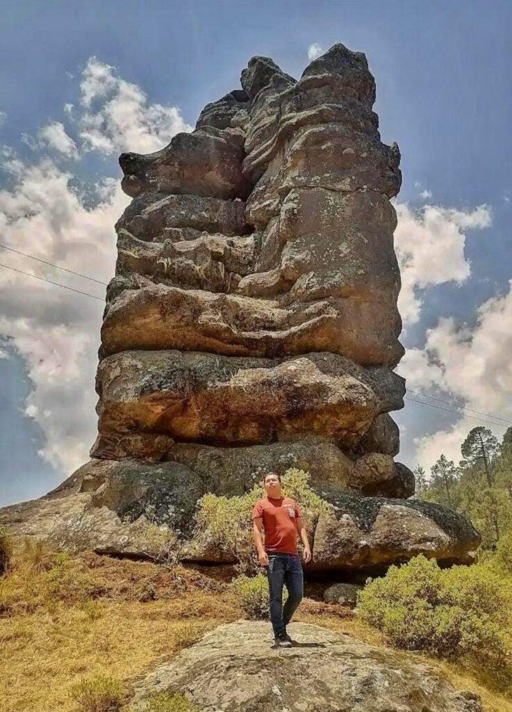 person standing in front of a large towering rock
