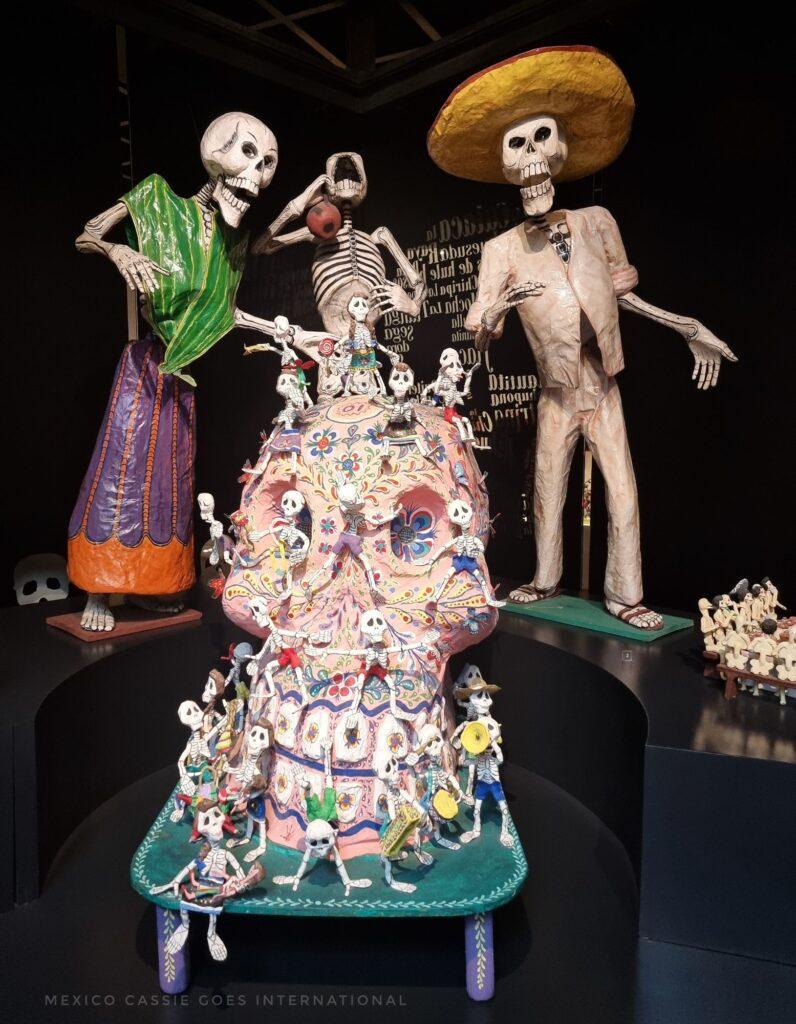 3 calaveras, behind a skull that has more calaveras around it