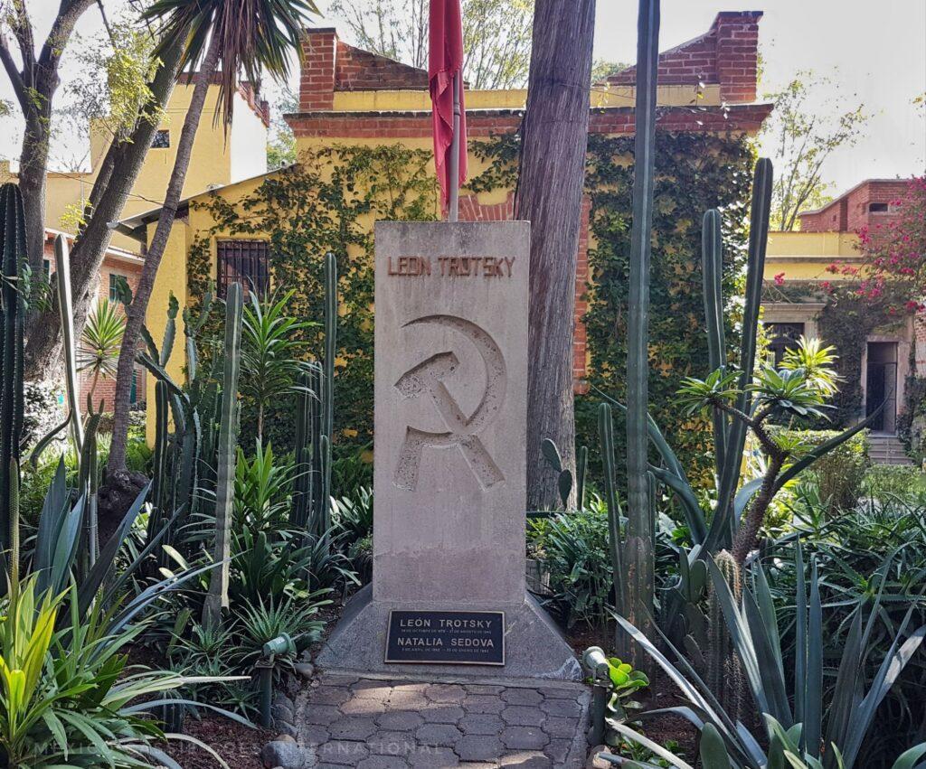memorial stone to Trotsky and his wife. Engraved with Soviet hammer and sickle. Plants around it