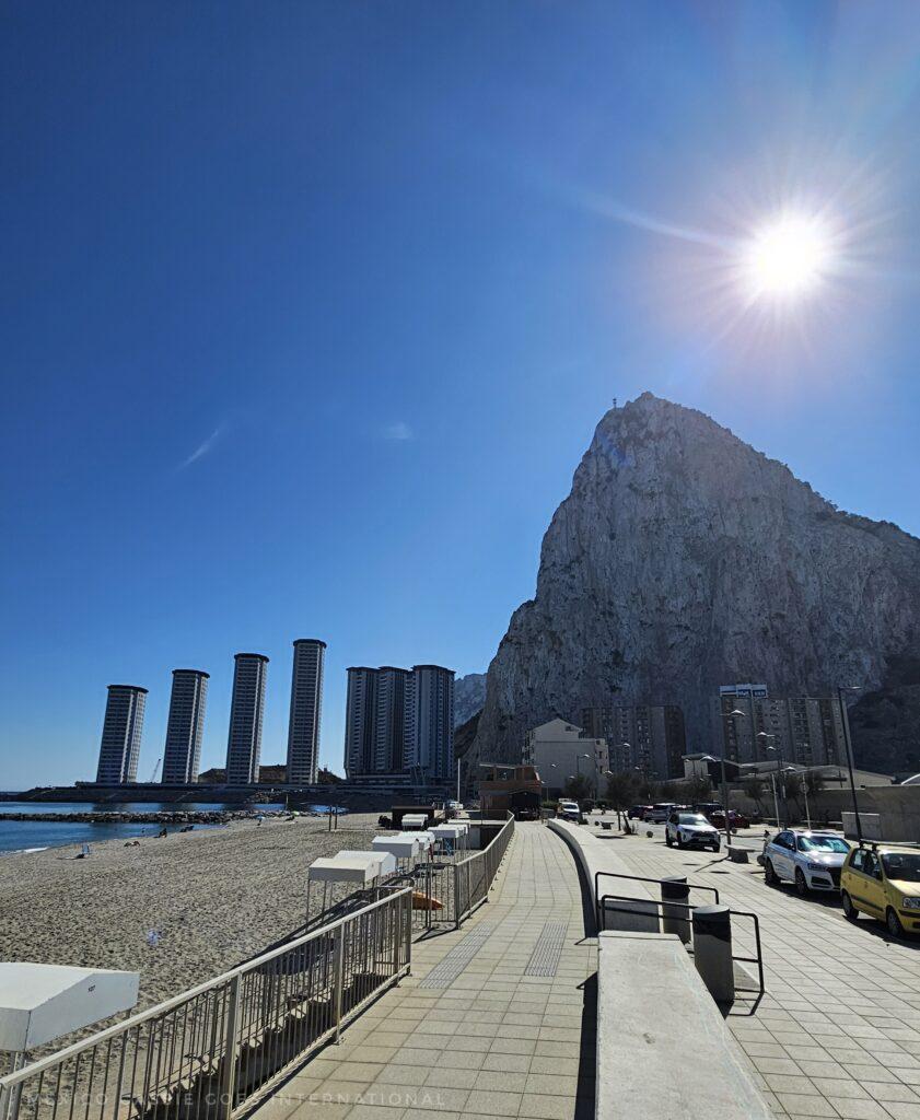 gibraltar's eastern beach, the rock on right, 4 tall blocks of flats in front and calm beach on left