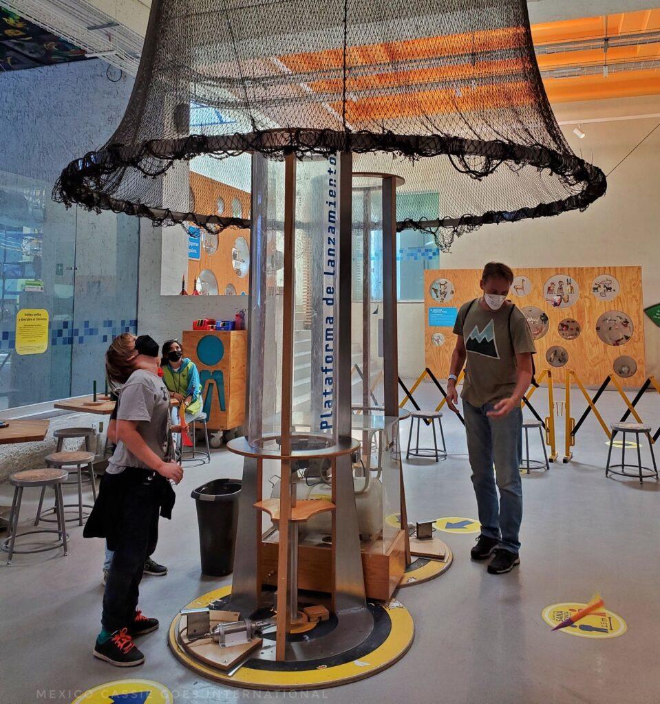 man and boy  looking up into a net at a science museum

