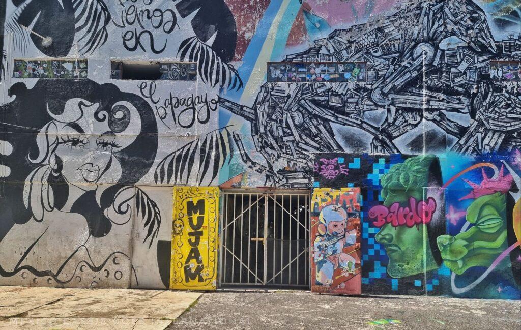 barred door to MUJAM museum (one door says MUJAM vertically,. other door and rest of wall is covered in mural art