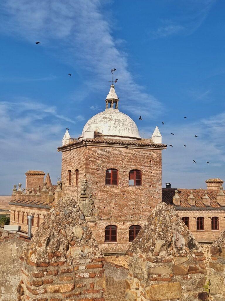 square tower with white dom at top, birds flying around dome