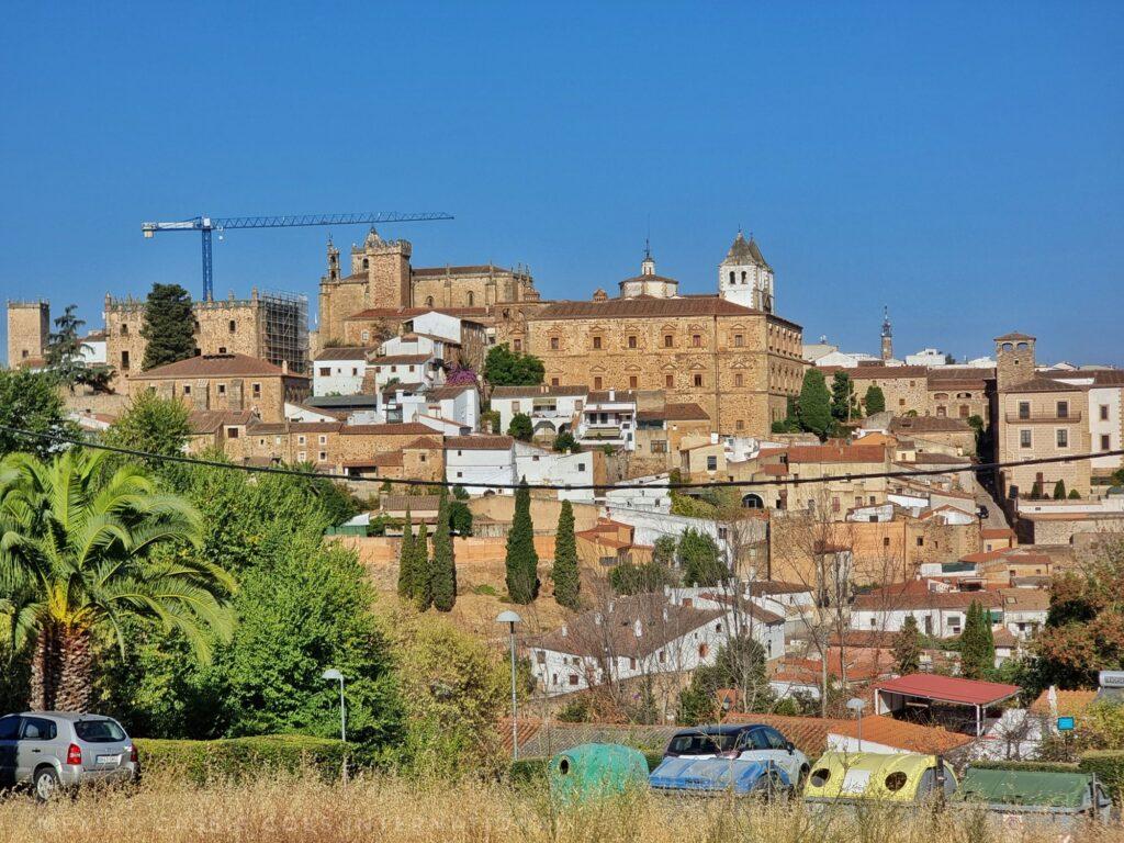 view over the old city of Cáceres with trash bins and a silver car in foreground, crane over city