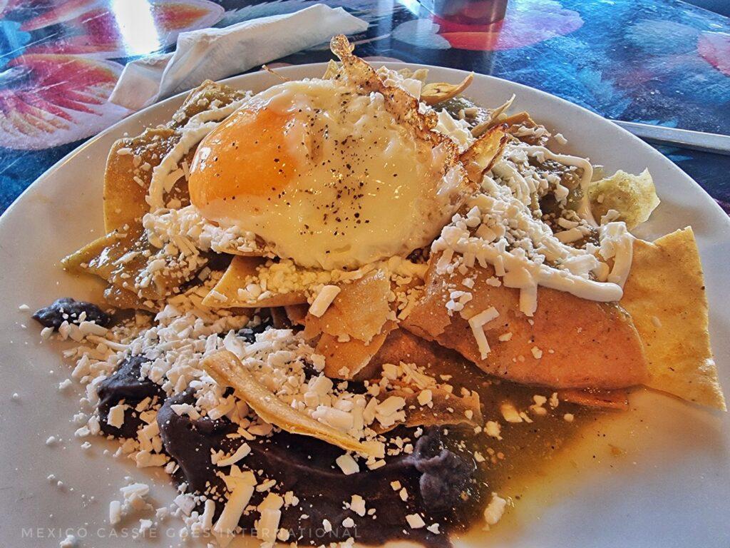 plate of Mexican breakfast - totopos, chicken, egg, beans, cheese salsa