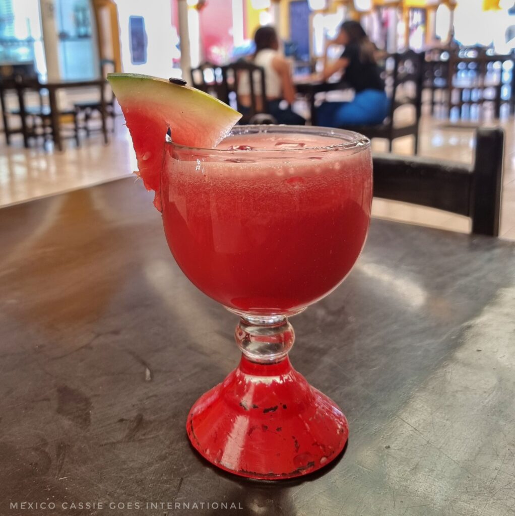 glass of watermelon juice with a slice of watermelon on the side of the glass