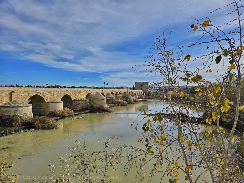 roman bridge, blue skies, brown still water