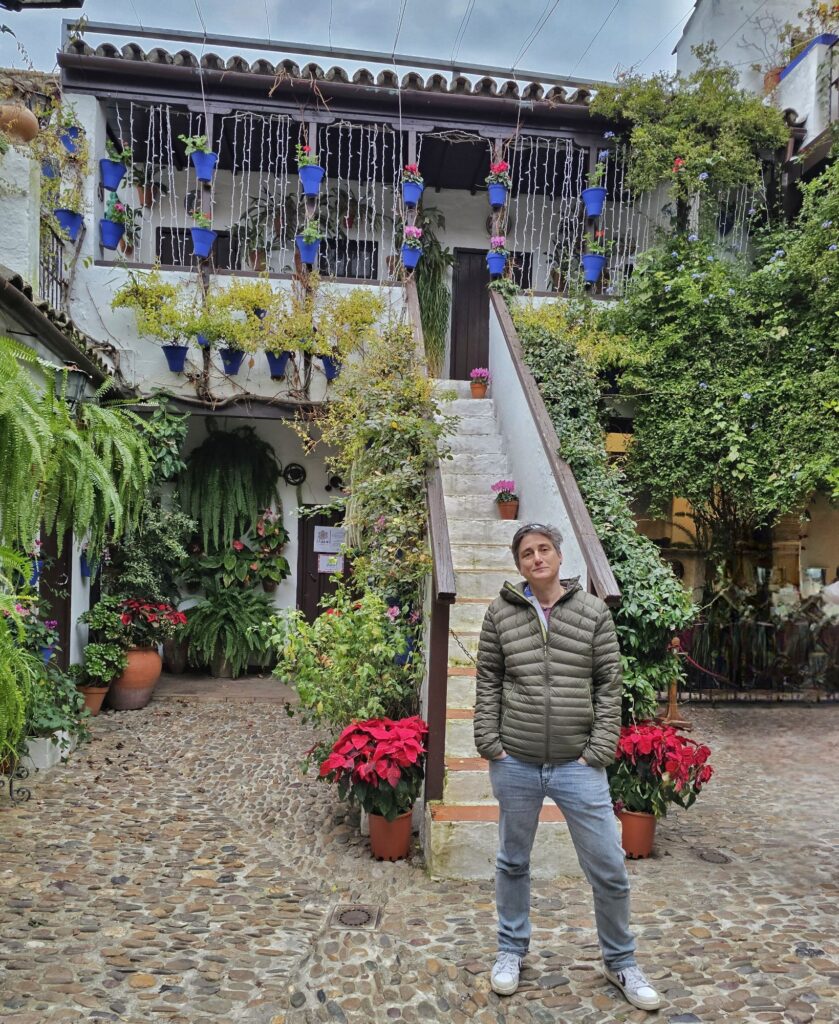 Cass standing in front of an outdoor staircase in a patio - flowers all around