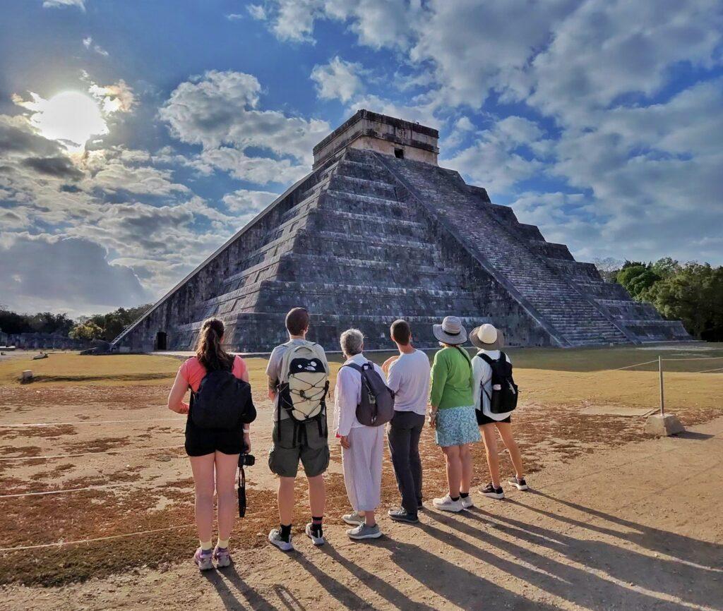 row of 6 people contemplating kukulkan pyramid