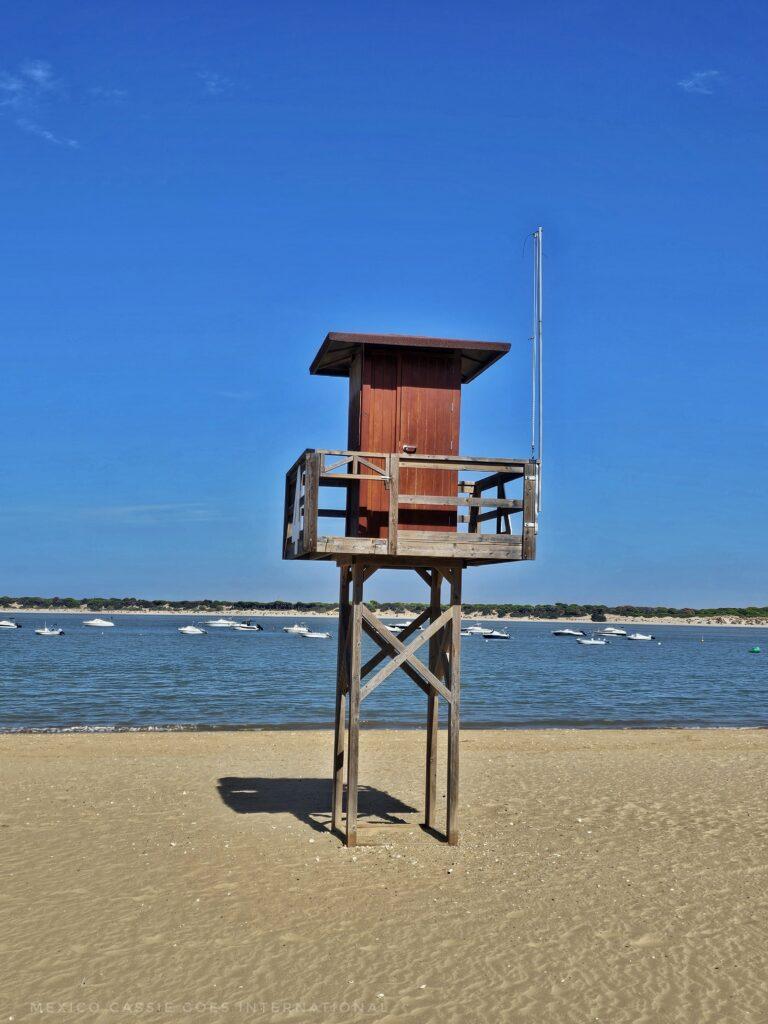 empty beach with wooden life guard stand and blue sky