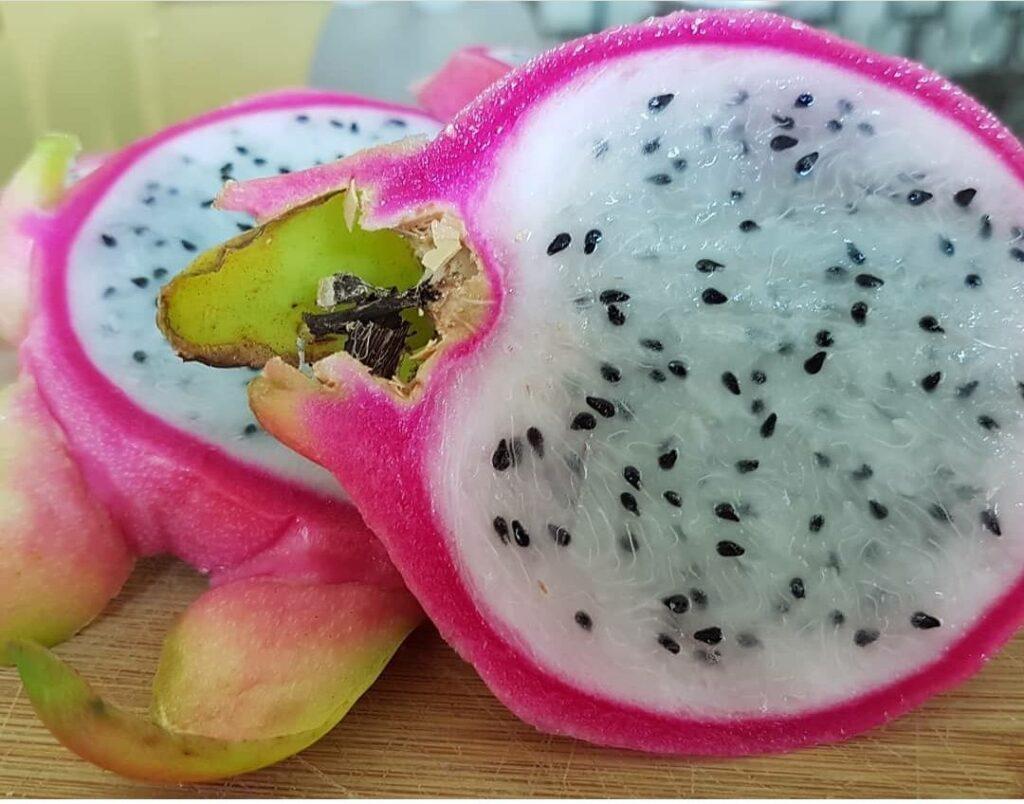 pink skinned pitaya with white flesh and black seeds - fruit cut in half