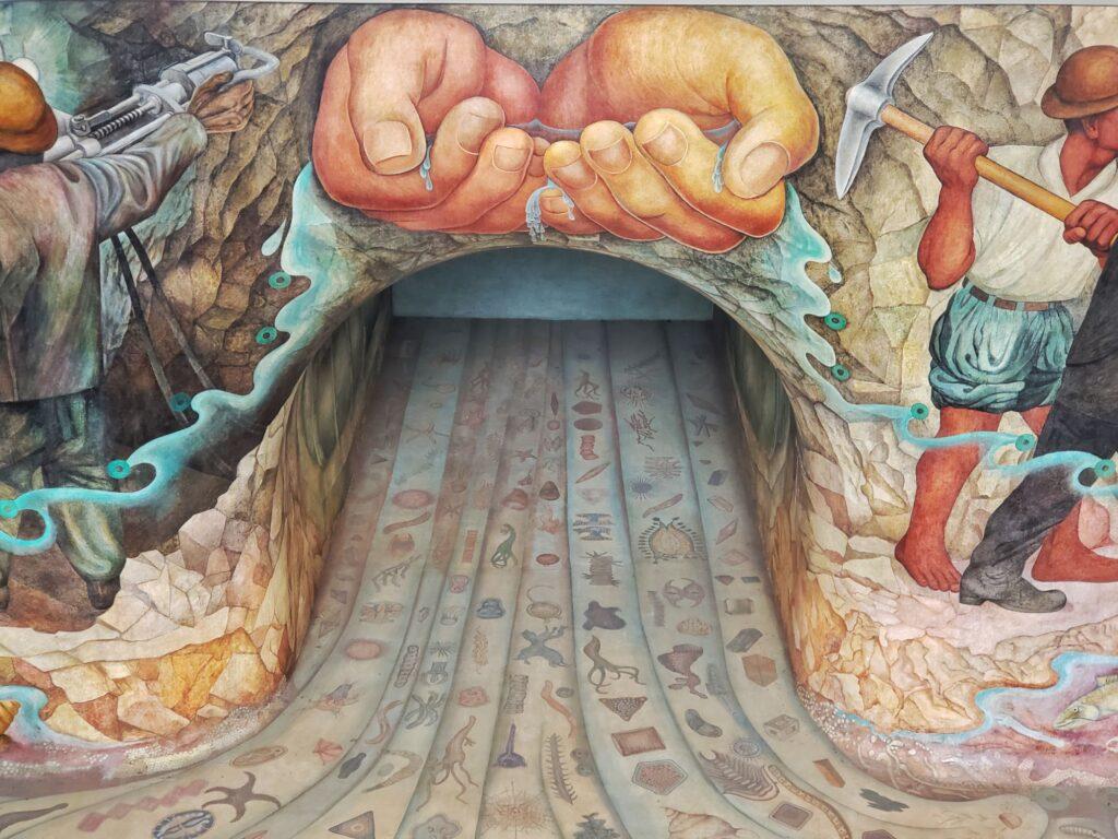 mural of hands cupping water above an arch, ground of arch is also painted with intricate items