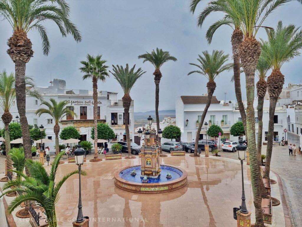 rainy day view over main plaza in vejer de la frontera, palm trees, white buildings, fountain 