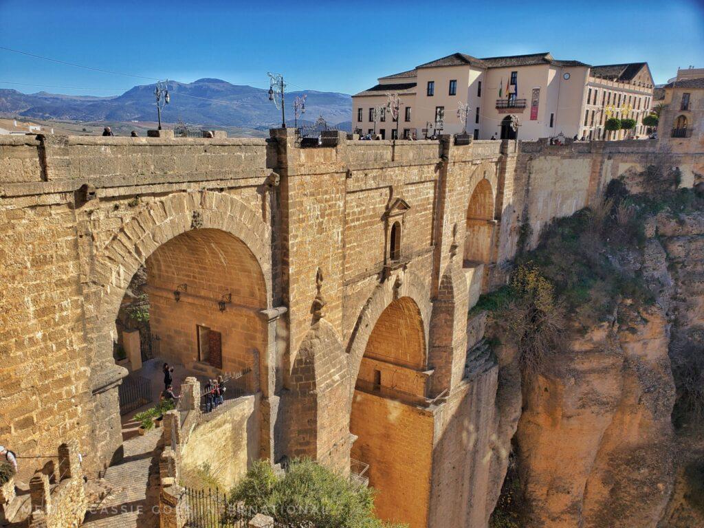 triple arched bridge, building on far side, blue sky