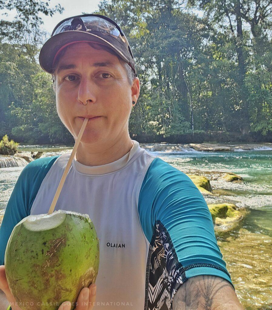 Cass in rash best and hat drinking fresh coconut