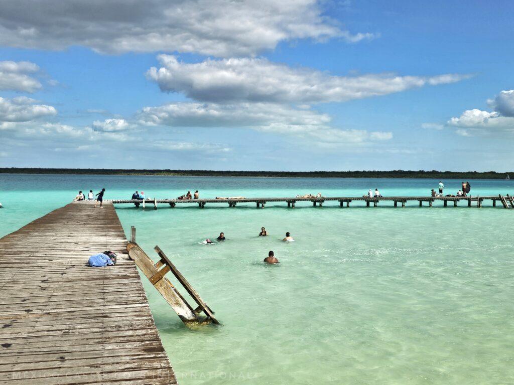 varying shades of beautiful blue / green water with wooden walk way, people in water and on walkway