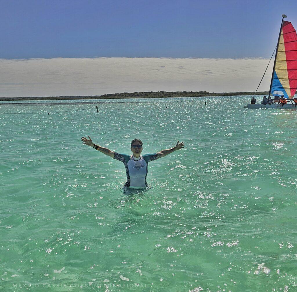 MexicoCassie in turquoise water, sail boat in background