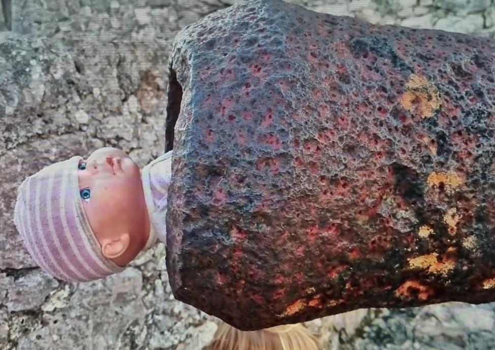 doll in purple and white hat sticking out the end of a cannon
