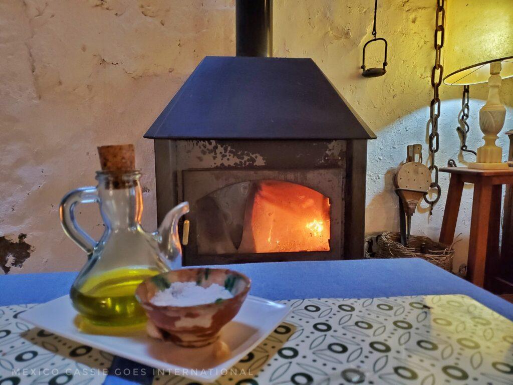 olive oil in clear jar and salt in a bowl. fire roaring in fire box behind