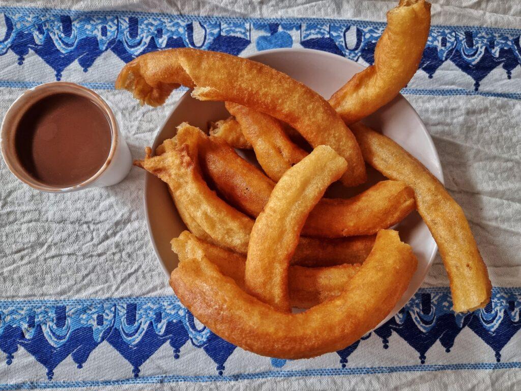 plate of churros next to a cup of chocolate