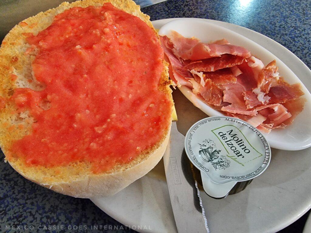 tomato on bread, plate of ham next to it