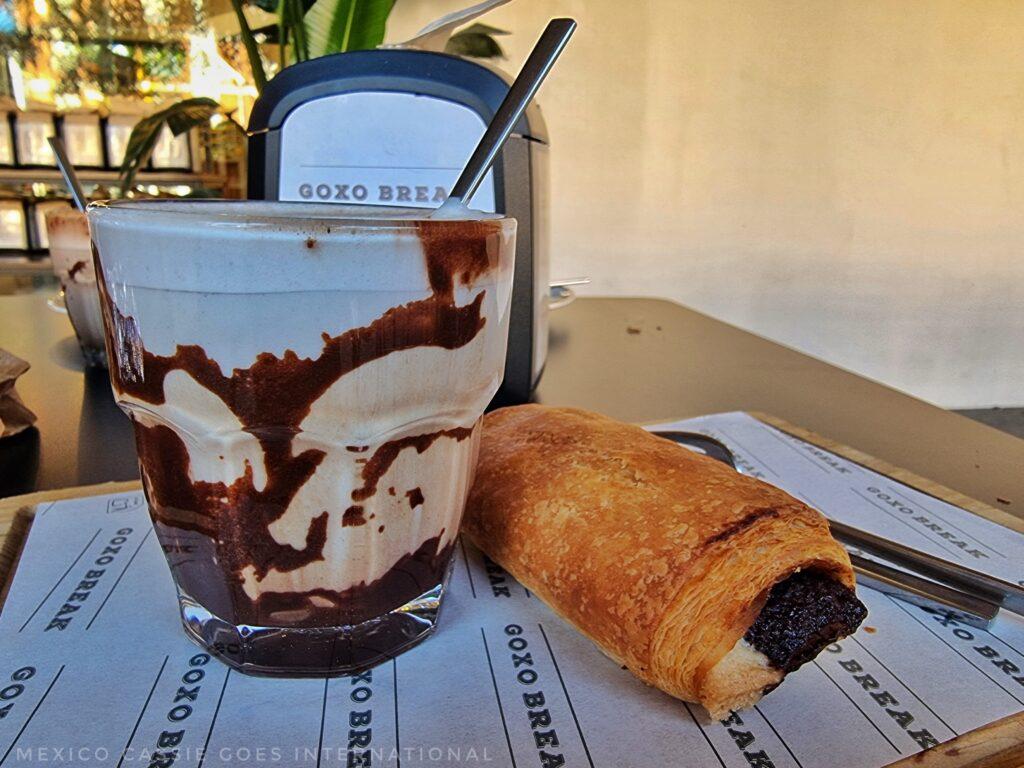 chocolate powder moving through milk in a glass next to a chocolatey pastry