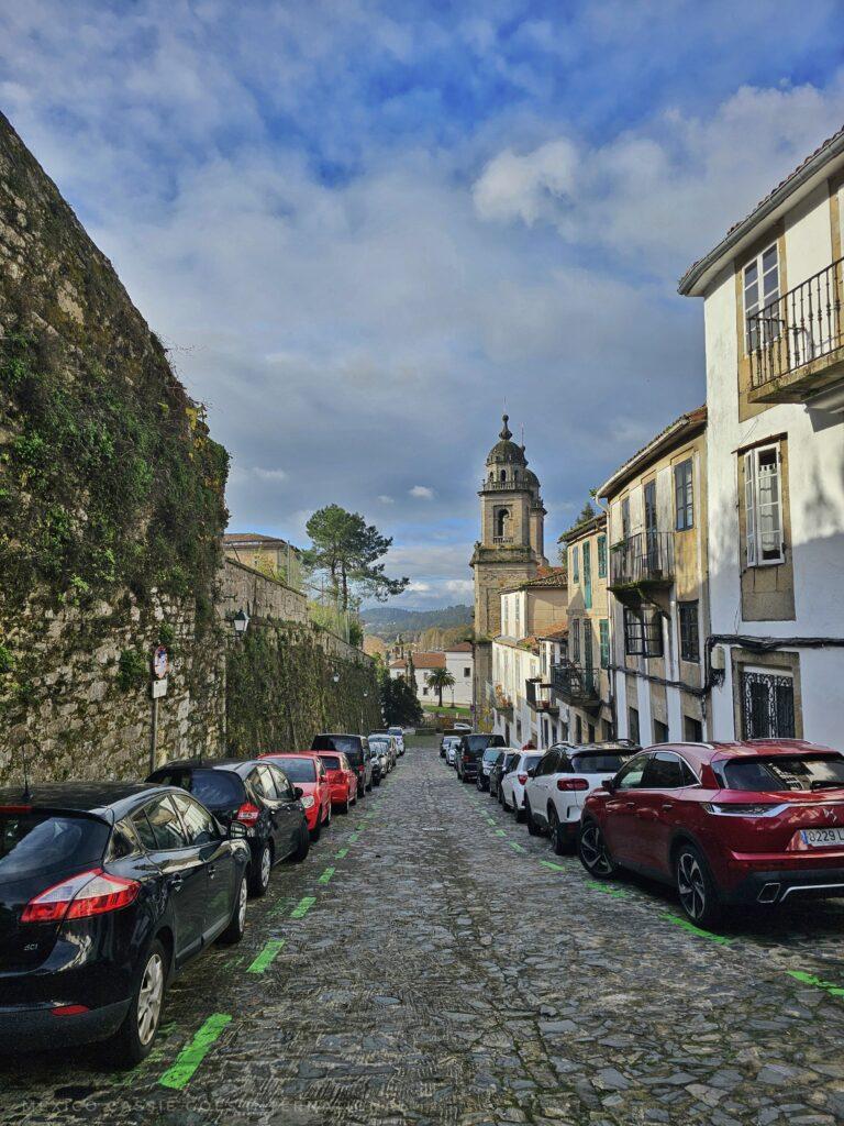 cars parked in spaces  market with green lines along a cobbled road