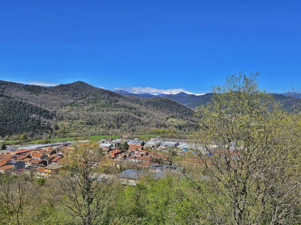 view from volcano crater in Olot - village, trees, hills, blue sky